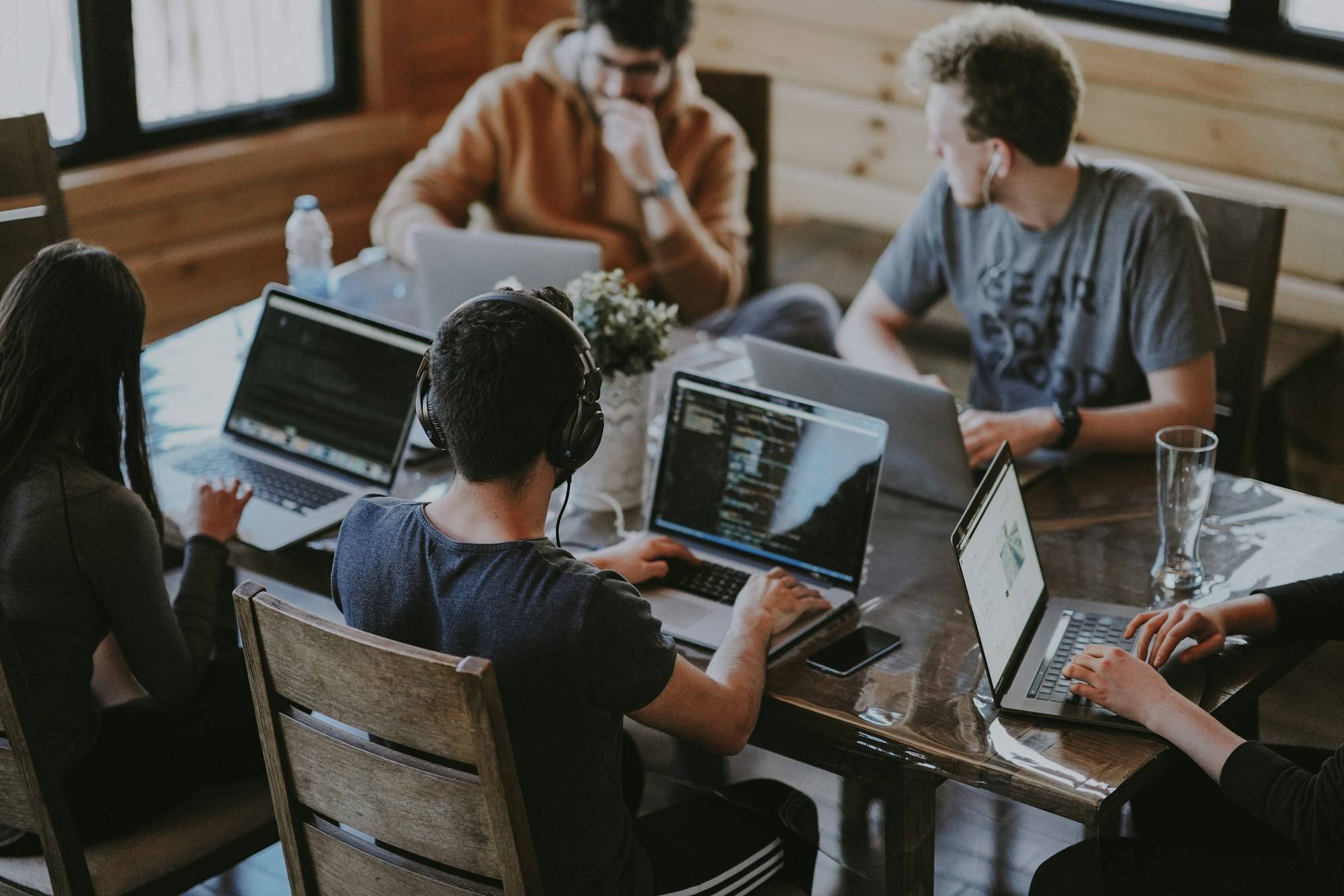 A team working together across several laptops at a shared table