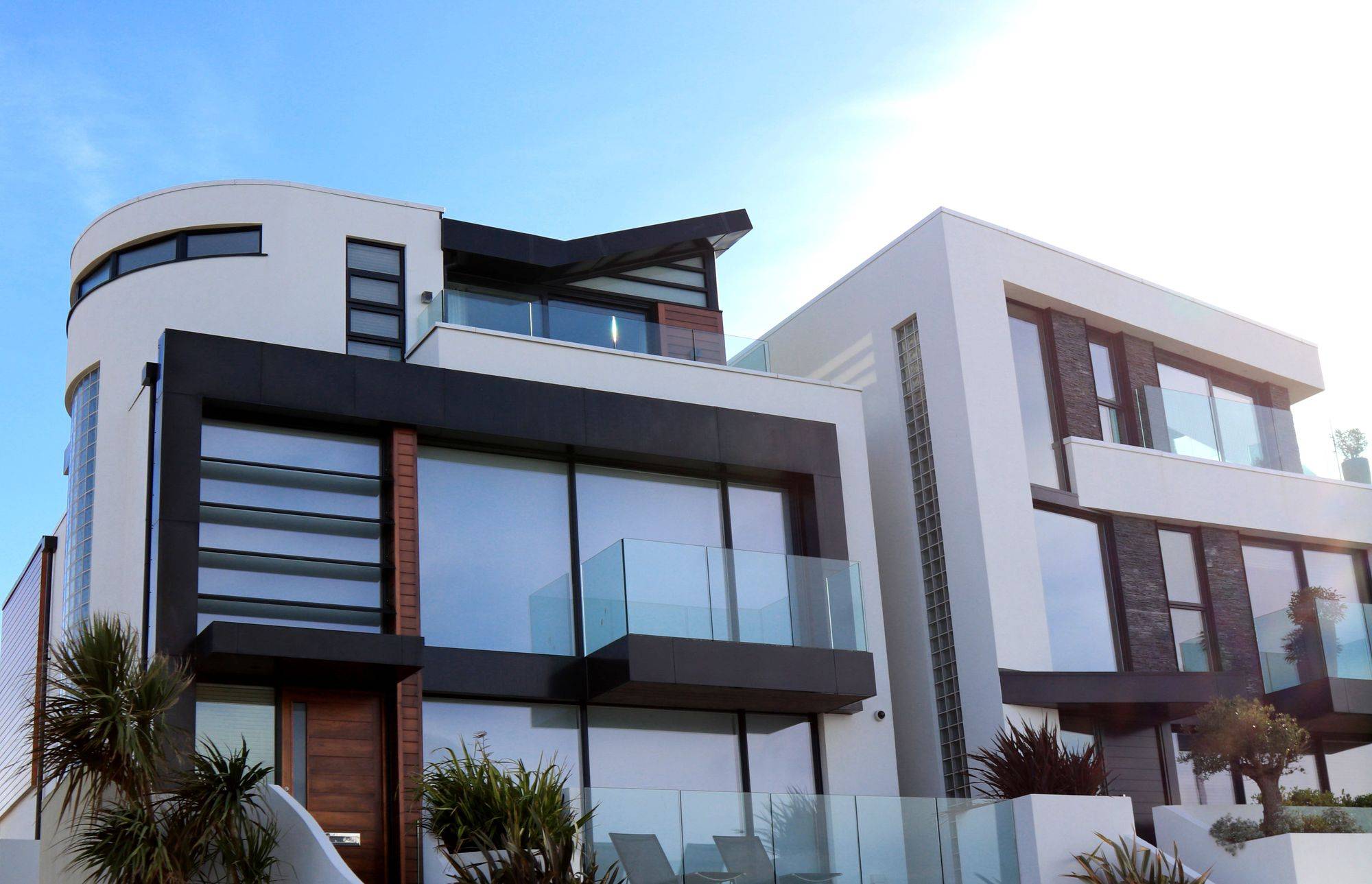 A modern residential building with glass balconies and a landscaped garden