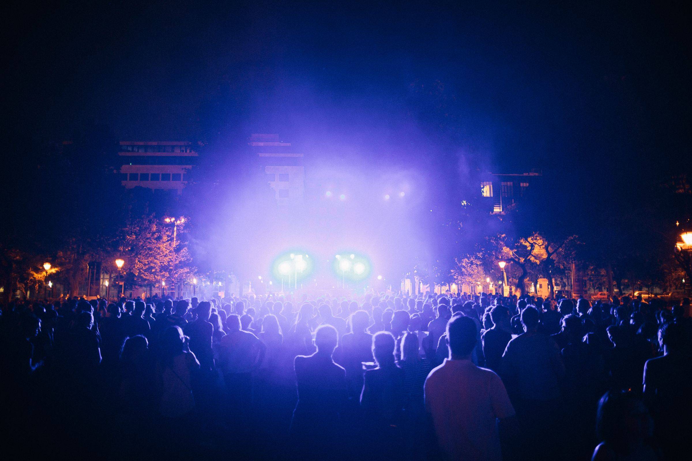 A festival crowd under stage lights at dusk