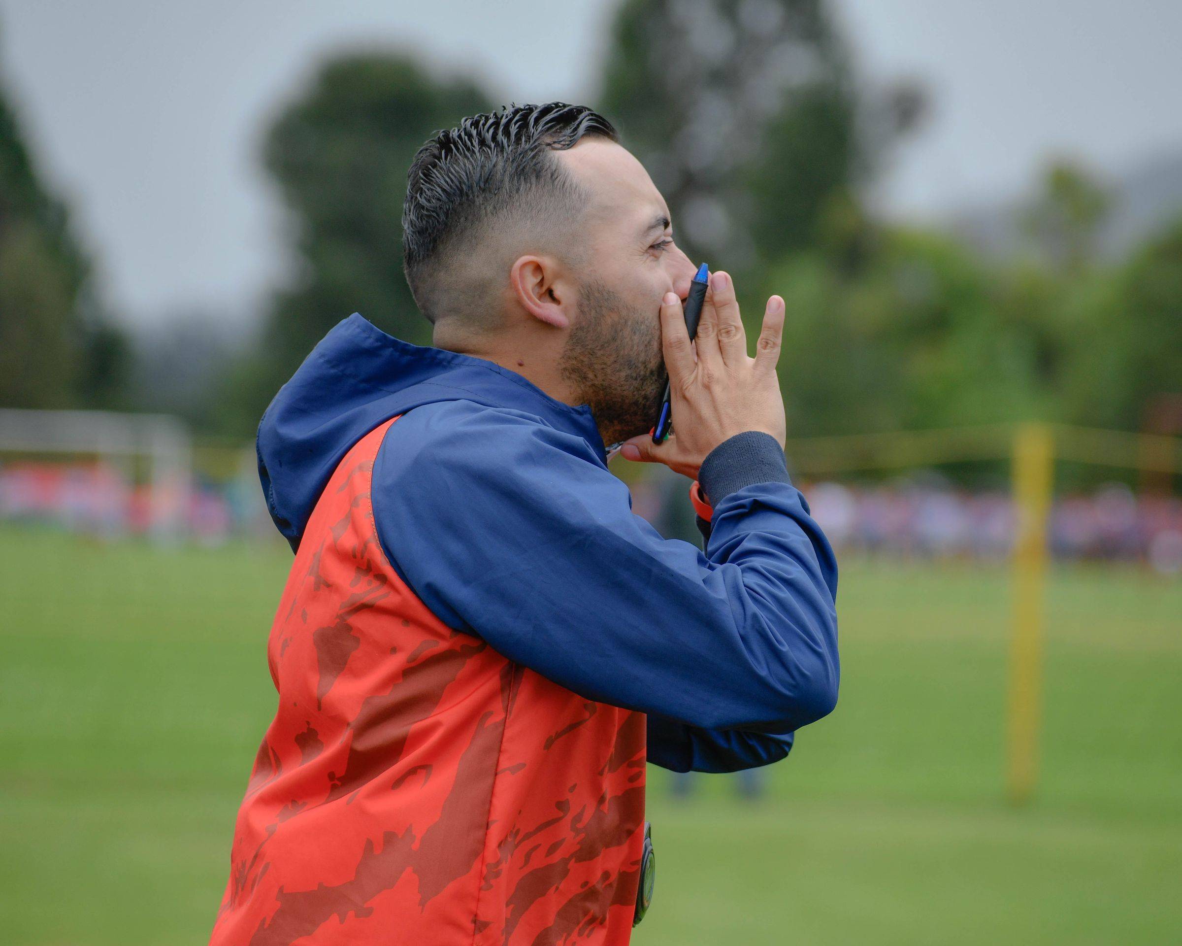 A coach calling instructions from the edge of a pitch