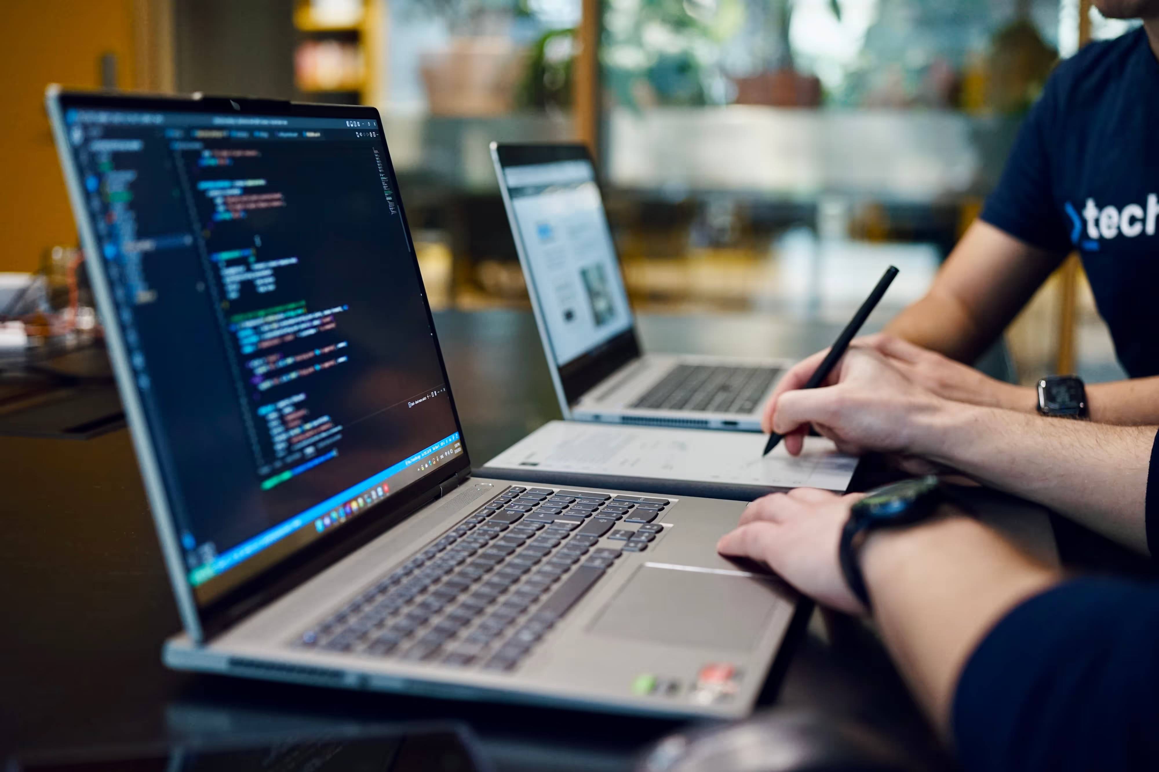 Techmates developers at two laptops with code open
