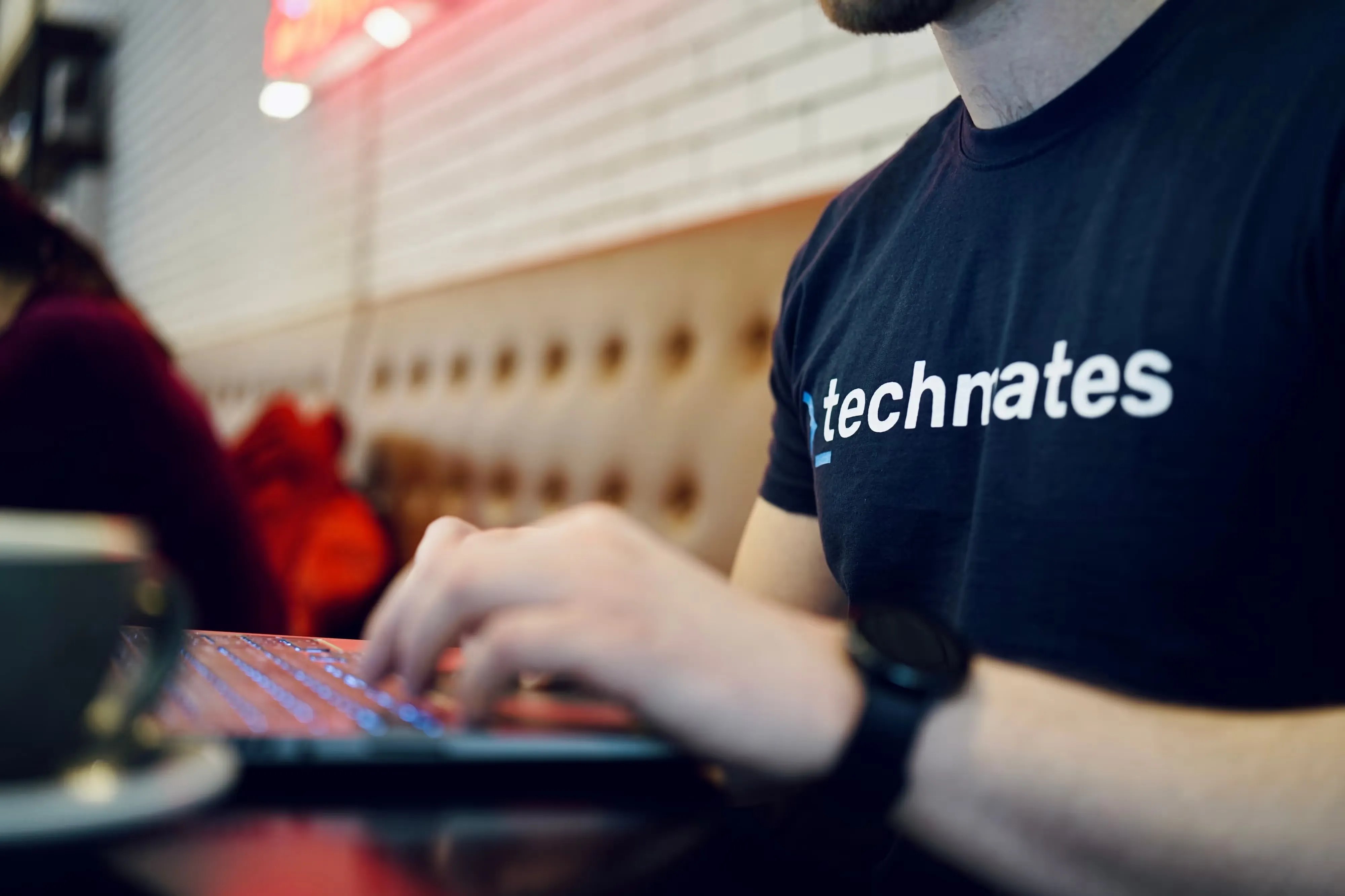 A Techmates team member in a team T-shirt working on a laptop